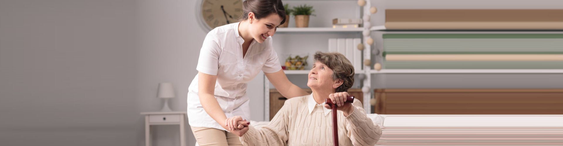 caregiver helping elder woman in standing up with an assistance of a walker